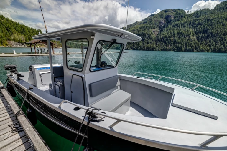 A ABD Rental boat is docked on a clear turquoise water with lush green mountains in the background and a partly cloudy sky above.